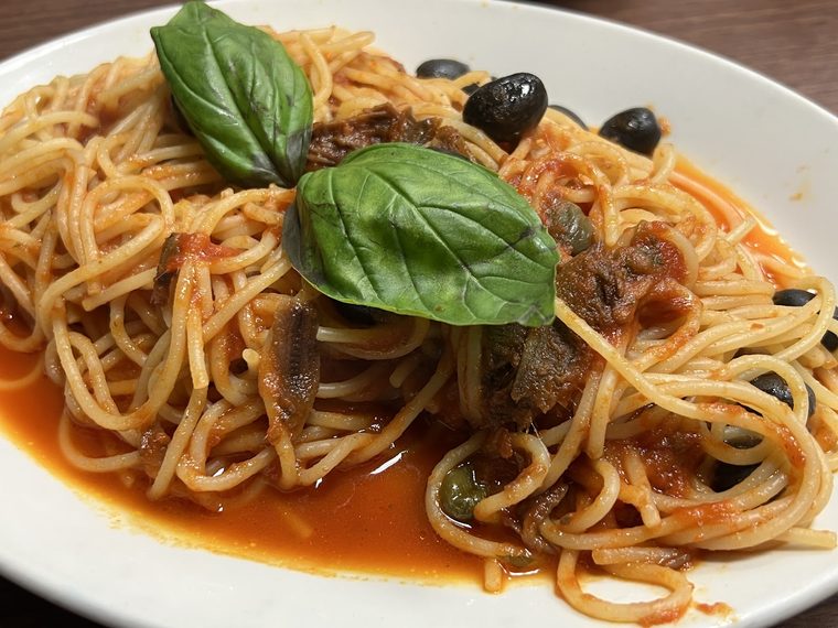 Plate of spaghetti in tomato sauce with olives and basil